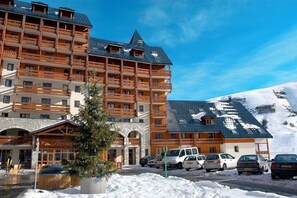 A multi-story hotel with a ski lift, snow-covered ground, and a mountain in the background. - Télécabine "Super Venosc" au pied de la résidence (Les Deux Alpes)
