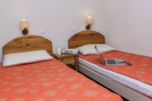 A double room with two beds, each with a wooden headboard, a nightstand, a lamp, and a laptop on one bed. - Piscine Intérieure | Au cœur du Parc de la Vanoise (Pralognan-la-Vanoise)