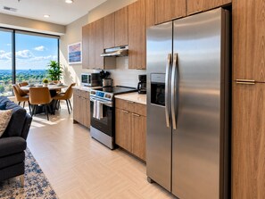 A modern kitchen with stainless steel appliances, wooden cabinets, and a dining area with a view. - Cityside Retreat | 2BR | Two Queen Beds (Birmingham)