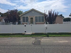 Uma casa residencial com portão fechado, varanda frontal e garagem.