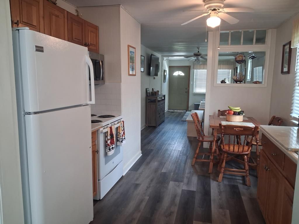 A kitchen with a refrigerator, stove, and wooden cabinets. There is a dining area with a table and chairs.