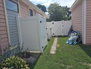 A fenced backyard with a pathway, a white gate, and a row of blue and white beach chairs. - Fenced Beach House w/ Deck & BBQ | Nr Delaware Bay (Villas)
