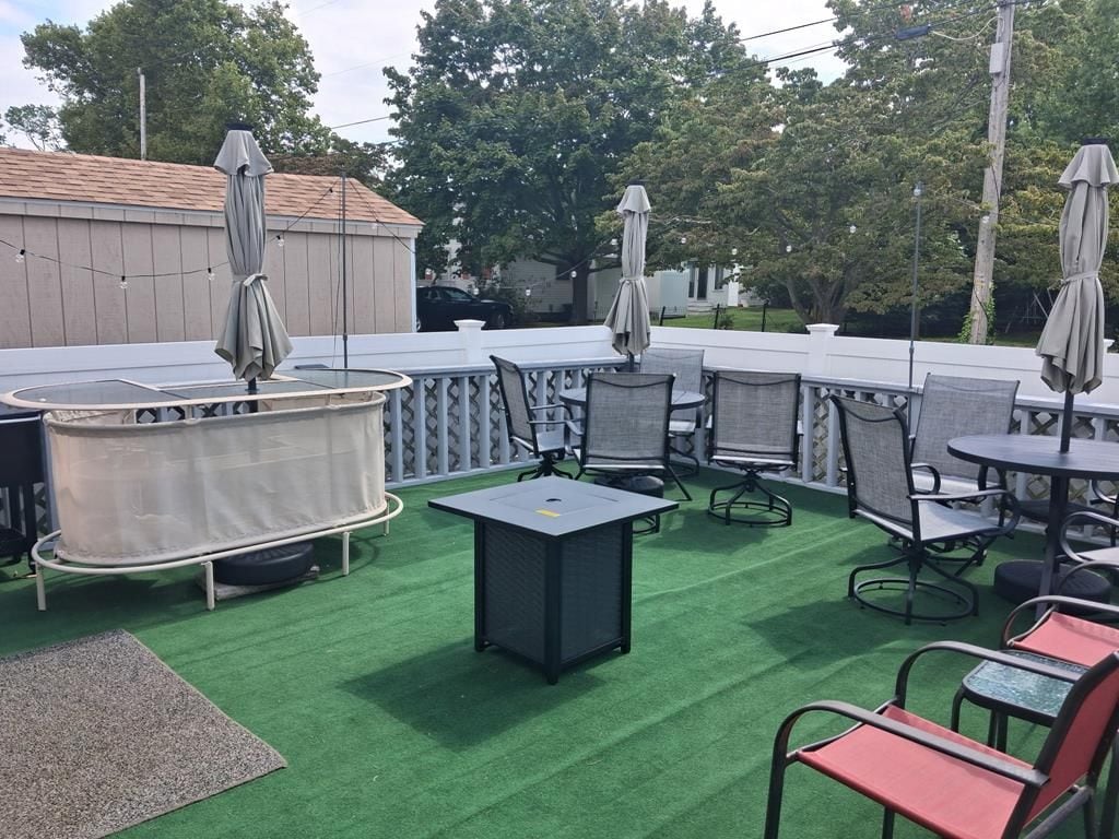 An outdoor patio area with tables and chairs, a covered seating area, and a view of the surrounding trees.