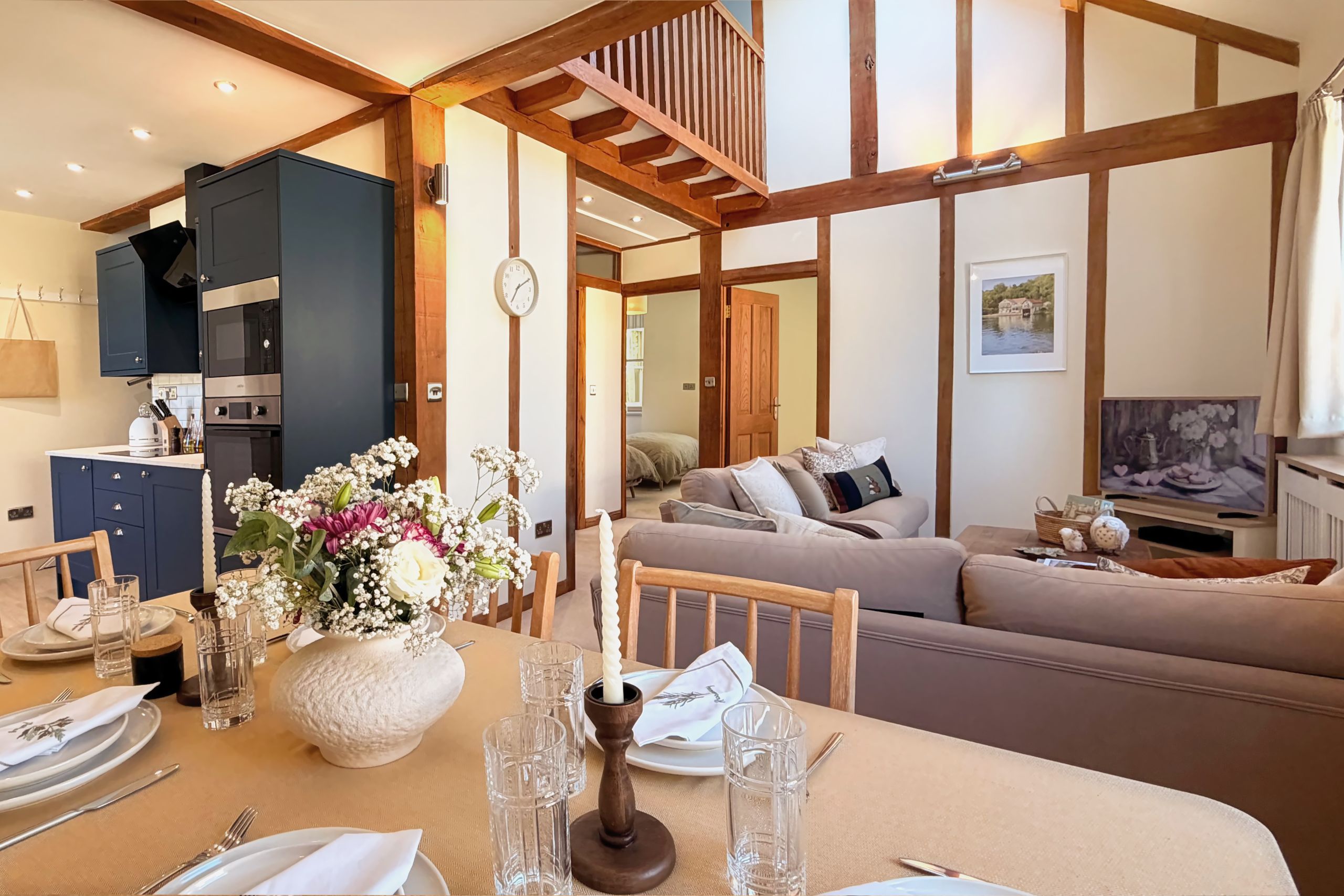 A modern living space with a dining area, kitchen, and a large window.