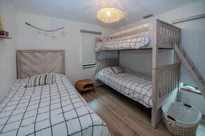 A bunk bed room with a wooden headboard, a hanging light fixture, and a small wicker stool. - Santa Clara: Modern 3BR Harborfront Retreat with Safety Harbor Club Access (Captiva)