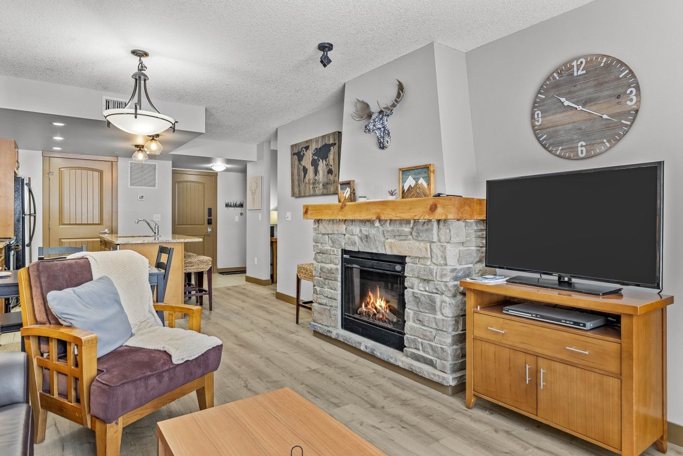 A living room with a fireplace, a television, and a clock on the wall.