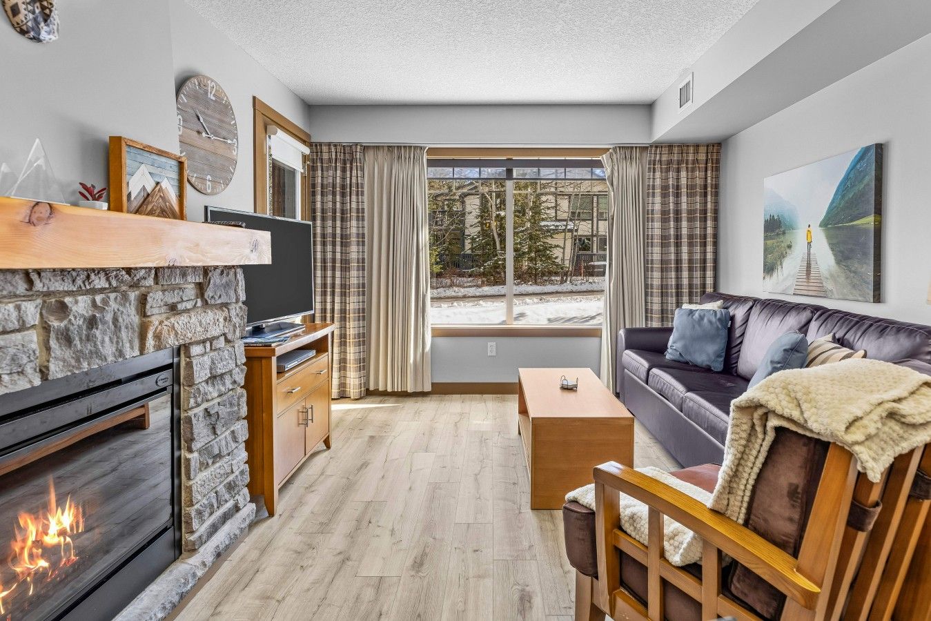 A cozy living room with a fireplace, a sofa, a coffee table, and a television.