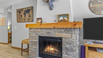 A living room with a stone fireplace, a mounted deer head, a world map, and a television.