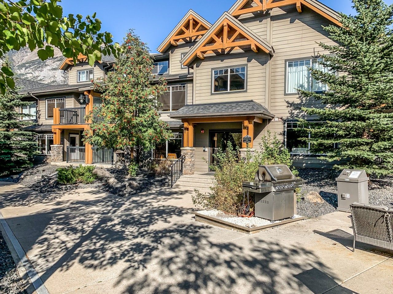 A residential area with multiple houses, a barbecue grill, and a small outdoor seating area.