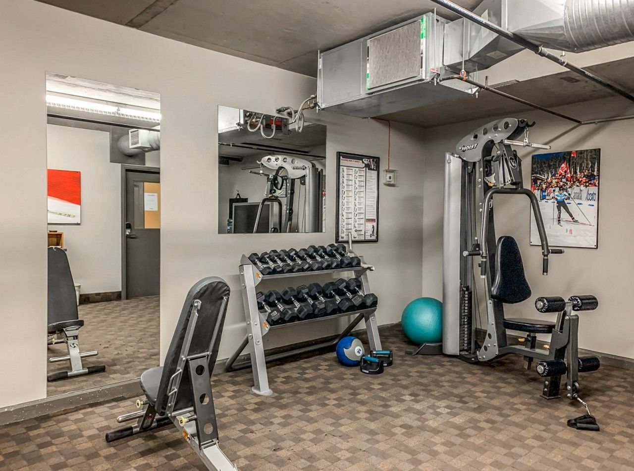 A gym with exercise equipment, a mirror, and a wall-mounted poster.