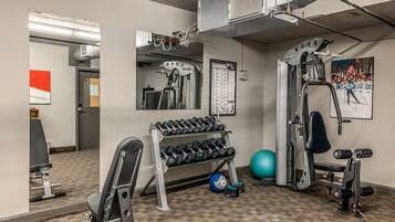 A gym with exercise equipment, a mirror, and a wall-mounted poster.