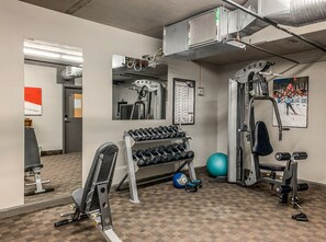 Ett gym med träningsutrustning, en spegel och en affisch som hänger på väggen.