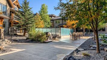 A patio area with outdoor seating, a stone wall, and a view of a building with a balcony.