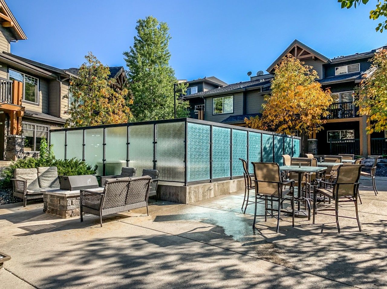 An outdoor patio area with seating and a grill, surrounded by a glass enclosure.