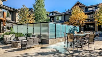 An outdoor patio area with seating and a grill, surrounded by a glass enclosure.