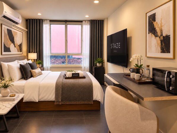 A modern hotel room with a bed, a desk, a television, and a window with curtains.