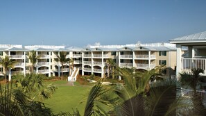 Um hotel com vários andares, varandas, um pátio central e palmeiras.