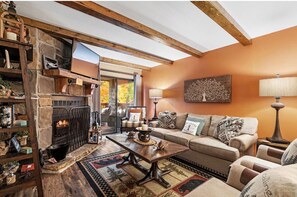 A cozy living room with a fireplace, a sofa, a coffee table, and a lamp. - Mountain Bear Retreat (Gatlinburg)