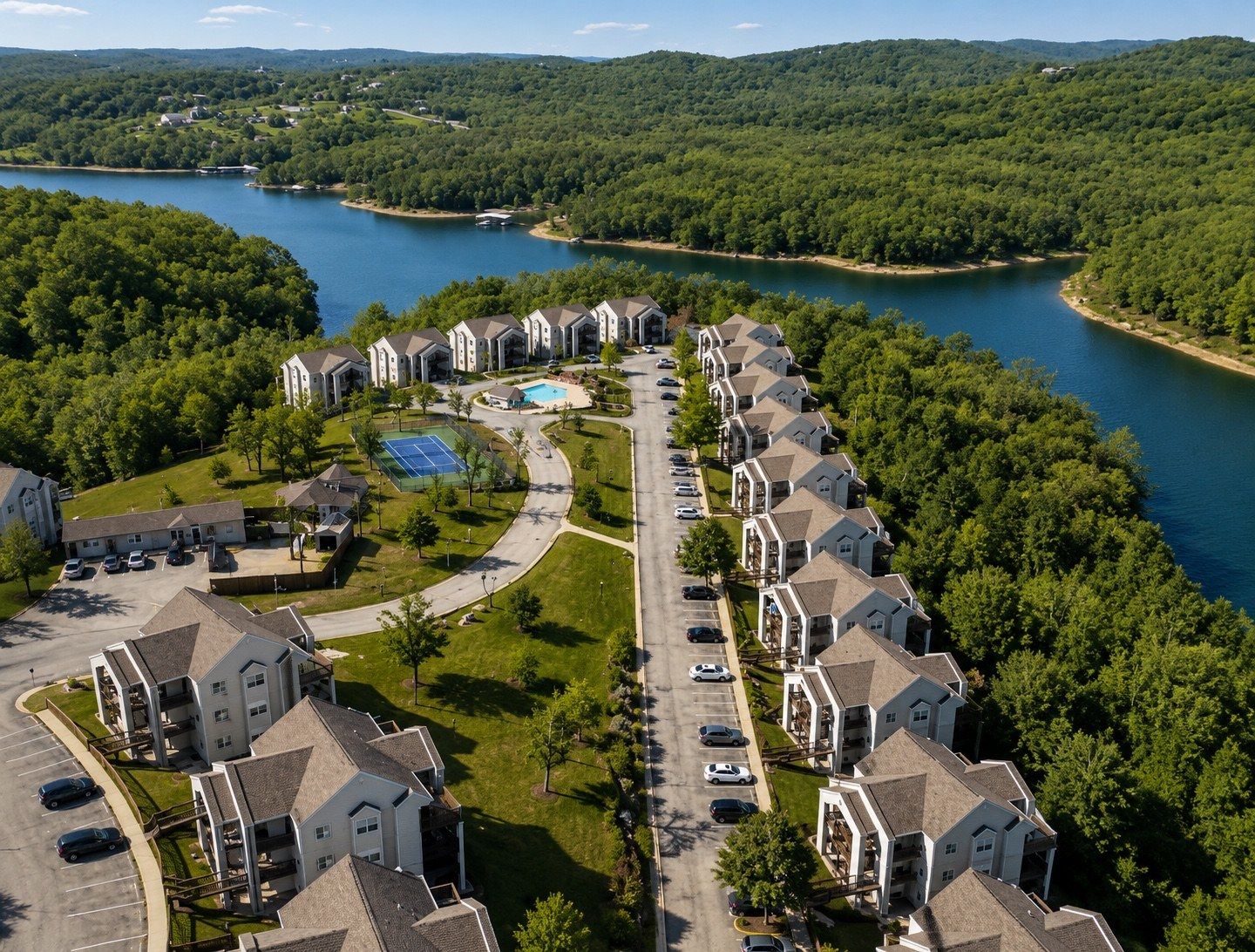 A residential area with houses arranged in a row along a curved road, a swimming pool, and a tennis court.