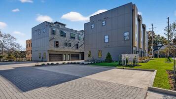 A modern building with a garage, paved driveway, and landscaped area.