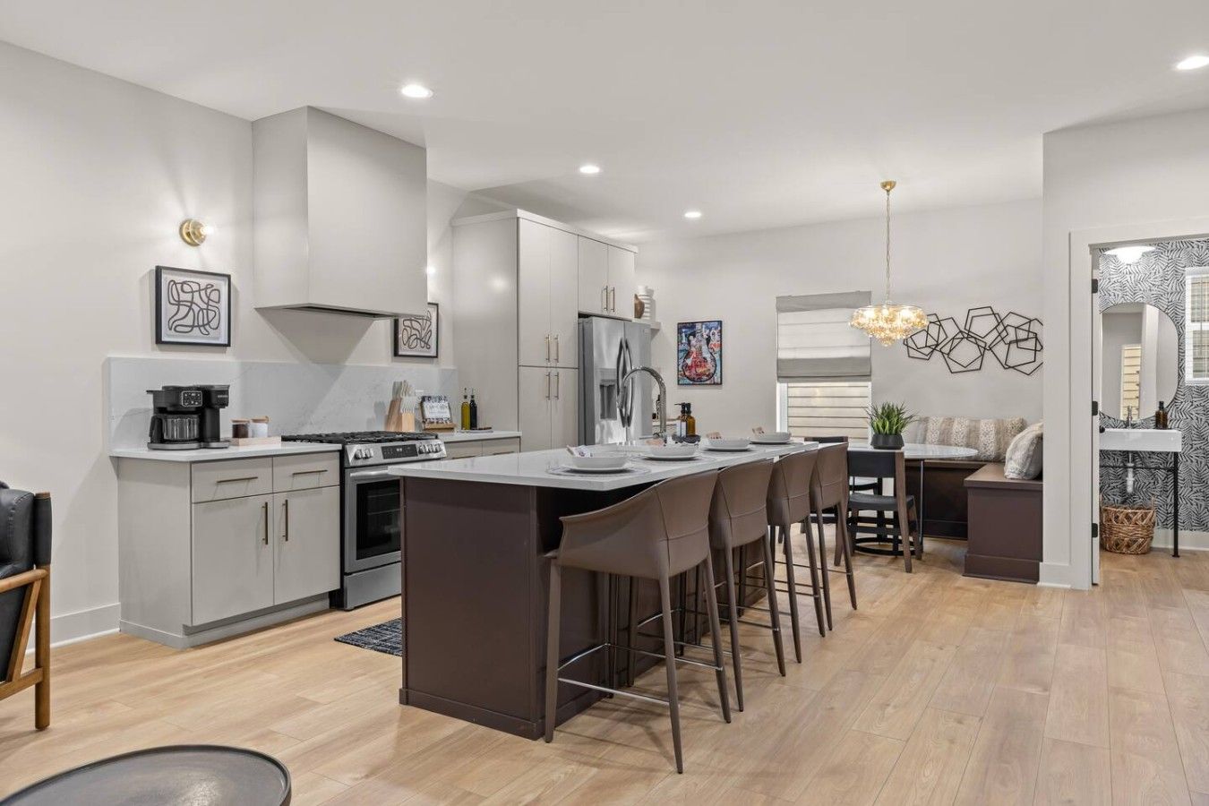 A modern kitchen with a central island, stainless steel appliances, and a seating area with a sofa and dining table.