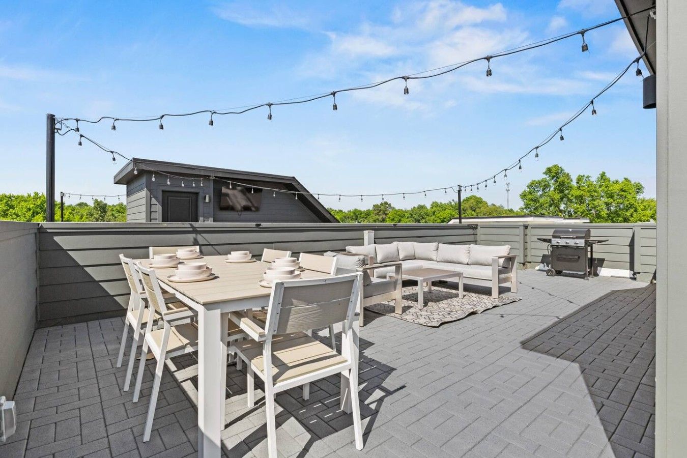 Une terrasse extérieure avec une table et des chaises, un canapé et un barbecue.