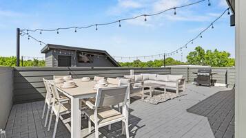 Une terrasse extérieure avec une table et des chaises, un canapé et un barbecue.