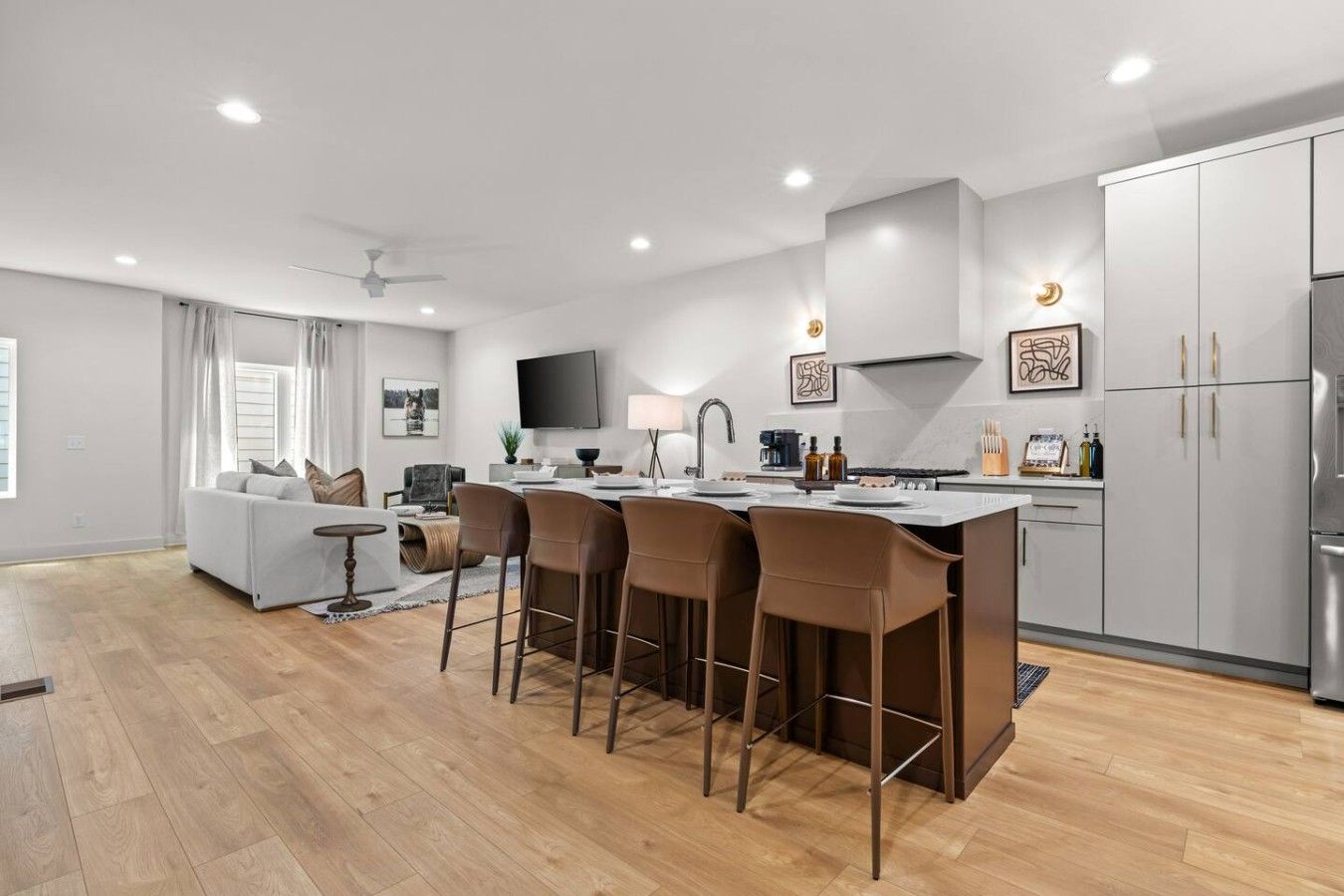 A modern kitchen with a central island, bar stools, a dining table, and a built-in oven.