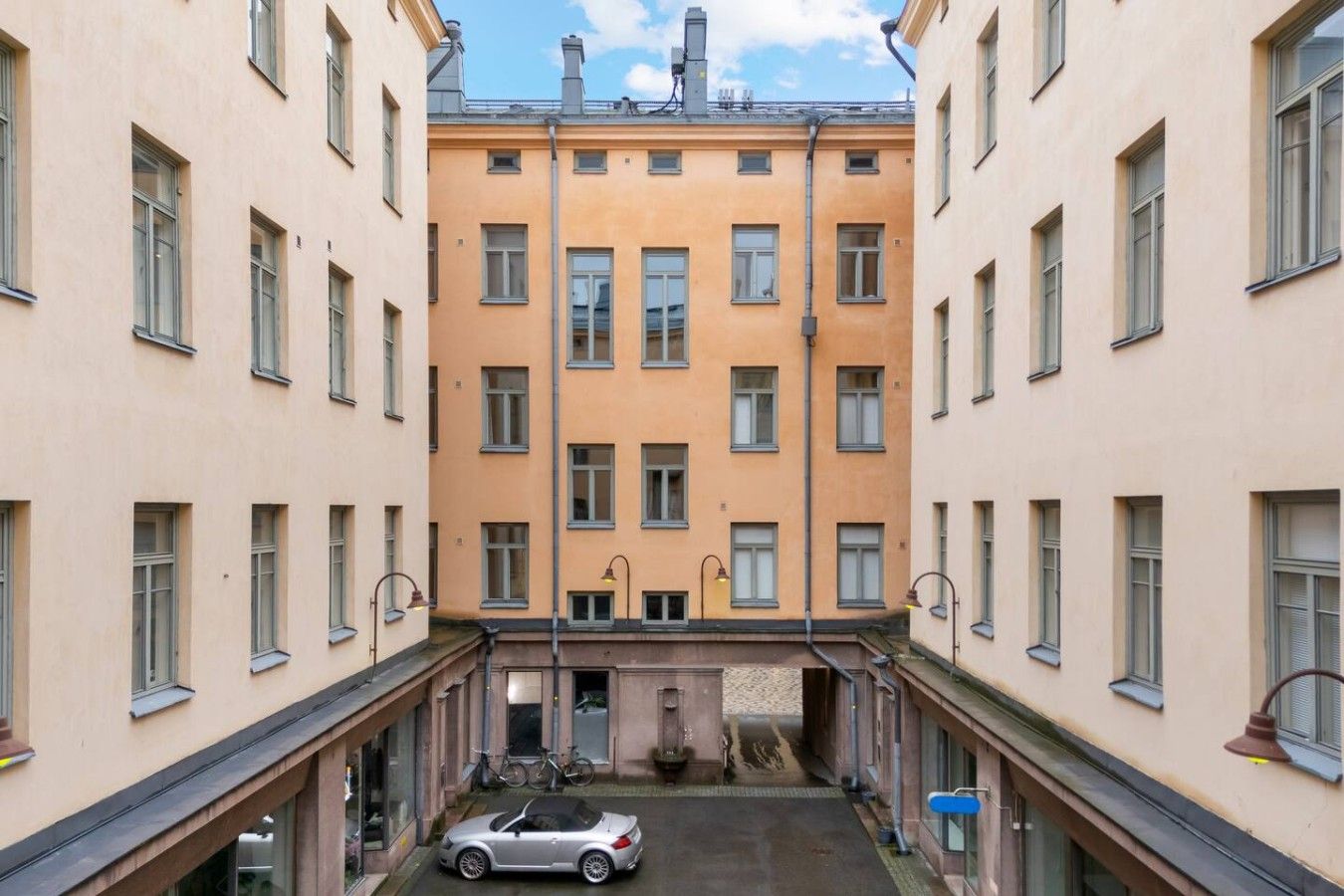 A multi-story building with a central courtyard, a parked car, and a bicycle.