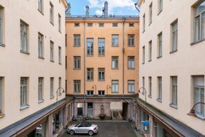 Monikerroksinen rakennus, jossa on keskeinen sisäpiha, parkkeerattu auto ja polkupyörä.