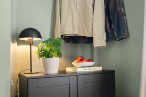 A bedside table with a lamp, a potted plant, a bowl of fruit, and a book titled 'DAN GRAHAM'. - 1875 Attic | Bathtub | Walking Street | Top Floor (Helsinki)