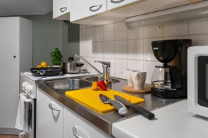 A modern kitchen with a stove, sink, and coffee maker. - 1875 Attic | Bathtub | Walking Street | Top Floor (Helsinki)