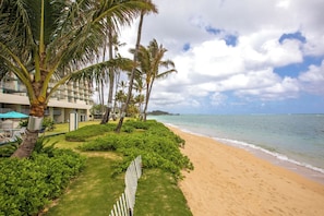 A beachfront hotel with a sandy beach, palm trees, and a clear view of the ocean. - Cozy 1-bedroom apartment with AC in serene Hauula (Hauula)