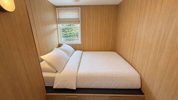 A compact room with a bed, a window with a view, and a ceiling fan.