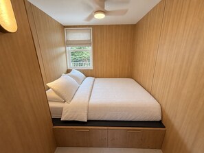 A compact room with a bed, a window with a view, and a ceiling fan. - Cozy 1-bedroom apartment with AC in serene Hauula (Hauula)