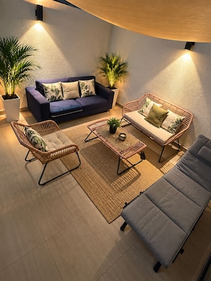 Een moderne woonkamer met een bank, twee fauteuils, een salontafel en een vloerlamp.