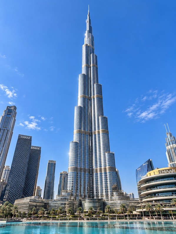 A tall, modern skyscraper with a distinctive tapering design, surrounded by other high-rise buildings and a waterfront.