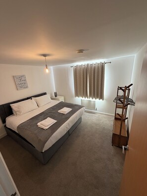 A bedroom with a bed, bedside table, and a wall-mounted light fixture. - Zana's Apartment/6 beds / Near Train Station and Town Centre (Ipswich)