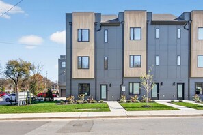 A multi-story residential building with a modern design, featuring a flat roof, large windows, and a symmetrical facade. - Rooftop with TV & BBQ, Garage, 3 Miles to Broadway (Nashville)