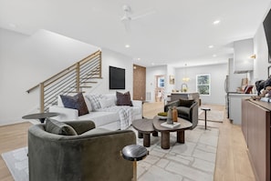 A modern living room with a staircase, a dining area, and a kitchen. - Rooftop with TV & BBQ, Garage, 3 Miles to Broadway (Nashville)
