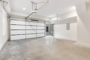 A spacious garage with a concrete floor, a closed garage door, and a ceiling-mounted projector. - Rooftop with TV & BBQ, Garage, 3 Miles to Broadway (Nashville)