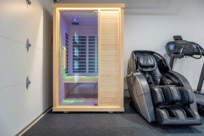 A sauna room with a wooden door, a massage chair, and a treadmill. - Waterpark View, Steps Away, Sauna + Arcade (Hurricane)