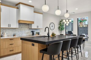 Una cocina moderna con una isla central, taburetes de bar e iluminación colgante.