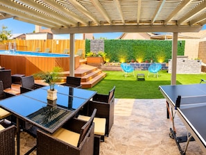 An outdoor patio with a pool, seating area, and a ping pong table. - 4-Bedroom Home • Pool • BBQ • Ping Pong • Near the Strip (Henderson)