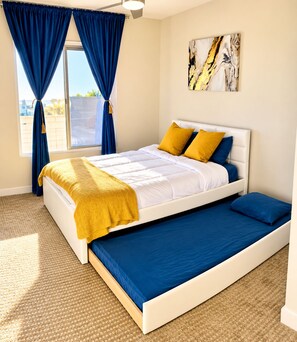 Ein Schlafzimmer mit einem Bett, einer Schlafcouch, einem Fenster mit Vorhängen und einem Bild an der Wand.