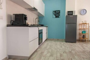 Una cocina compacta con microondas, horno y cafetera sobre la encimera.