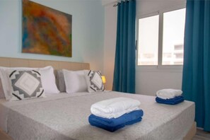 A hotel room with a bed, pillows, a painting, and a window with curtains. - Beachside • Balcony • Estoril Beach • Best Beach (Sal Rei)