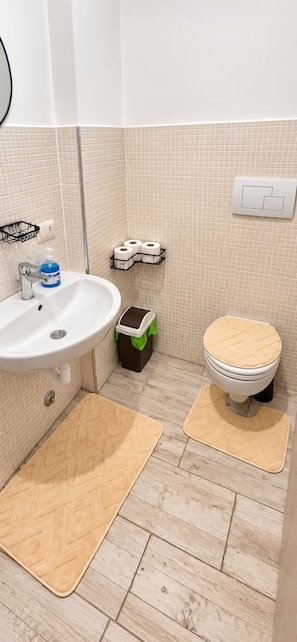 Une salle de bain avec un lavabo, des toilettes et une poubelle.