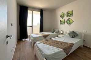 A hotel room with two beds, a sliding glass door, and a view of the outdoors. - Ocean View Retreat with Rooftop Terrace & Beach (Sal Rei)