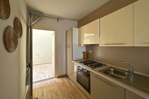 A kitchen with a gas stove, sink, and wooden cabinets. - Ocean View Retreat with Rooftop Terrace & Beach (Sal Rei)